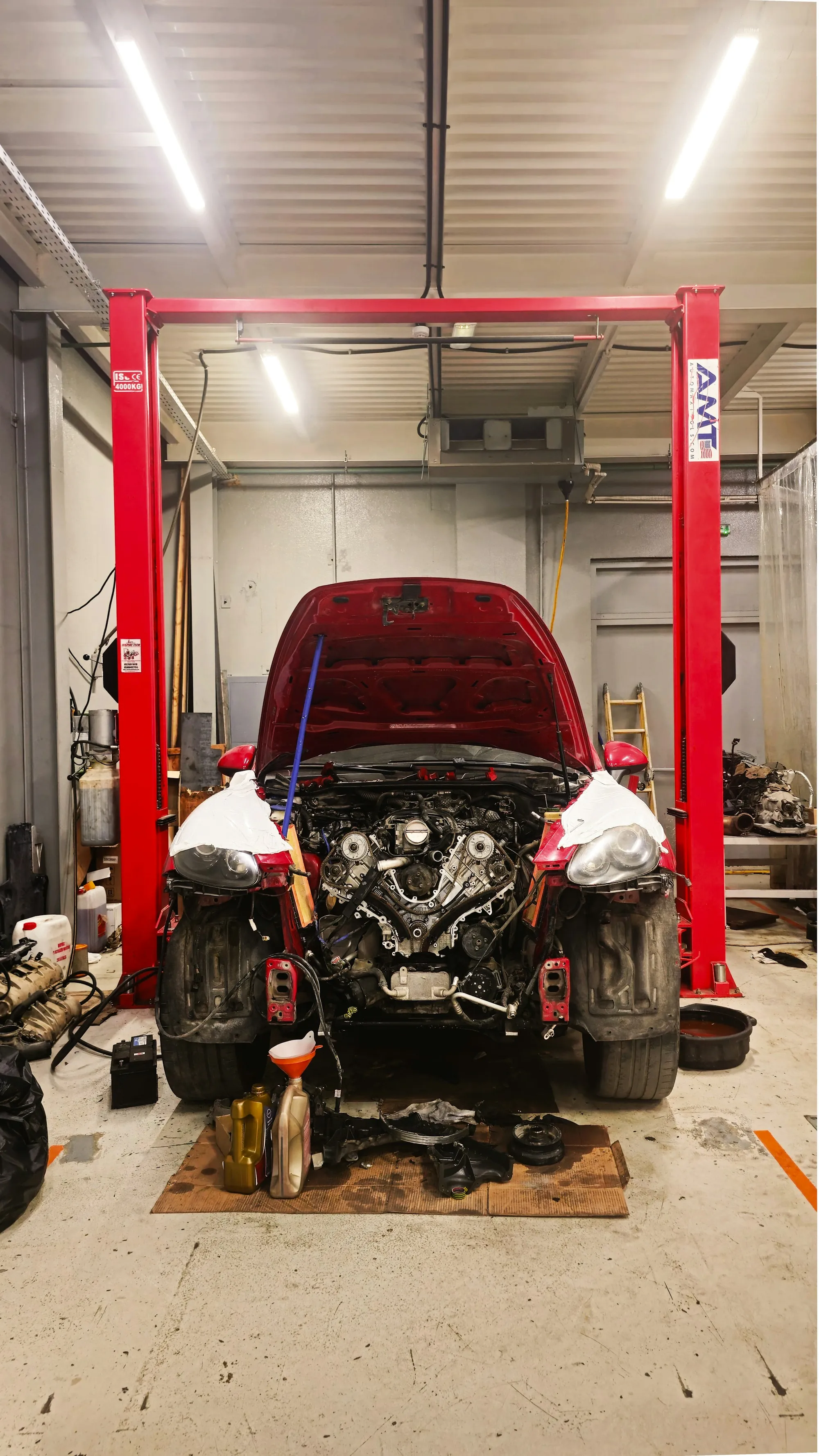 Car raised on a red lift with its front end opened up